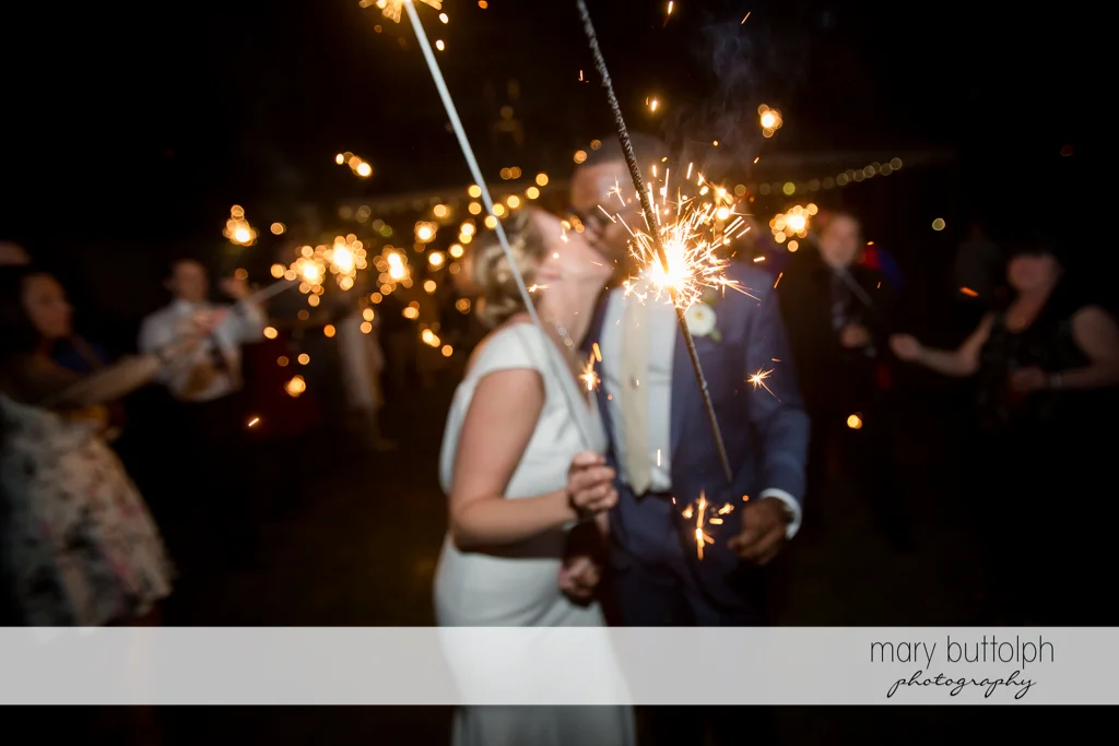 Couple kiss while holding sparklers at the Inns of Aurora Wedding