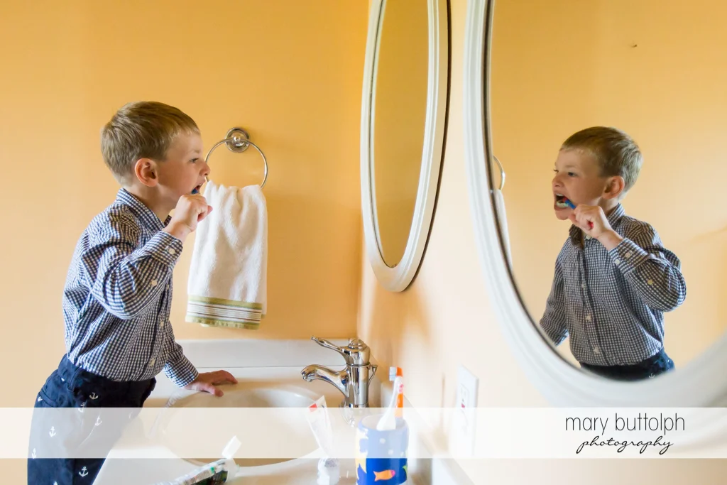 Boy brushes his teeth in front of the mirror at Skaneateles
