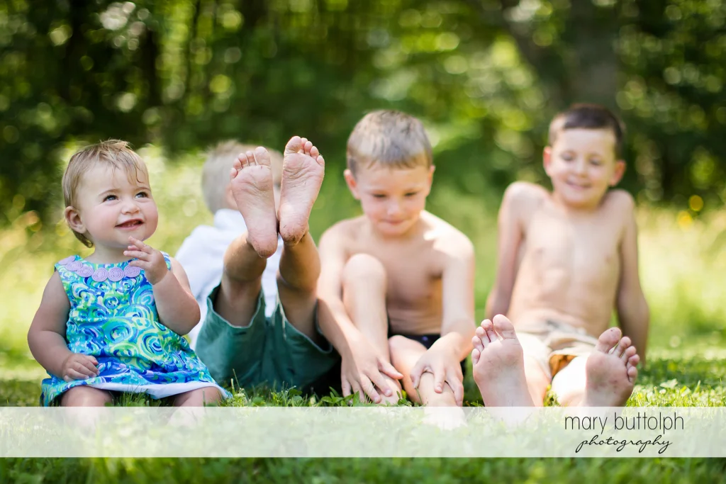 The siblings sit on the grass in the garden at Skaneateles