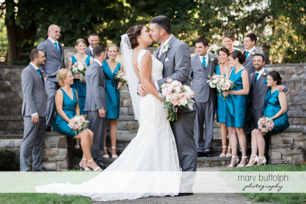 Couple kiss in front of the bridesmaids and groomsmen at The Lodge at Welch Allyn Wedding