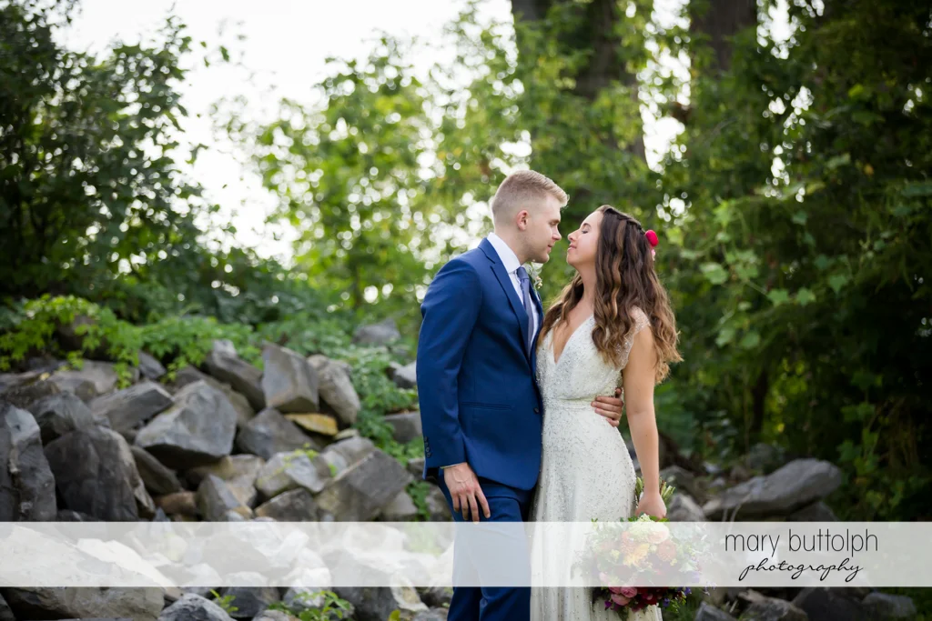 Couple pose in front of rocks in the garden at Aurora Inn Wedding
