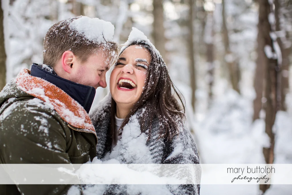 Couple laugh while covered in snow at Highland Forest Engagement