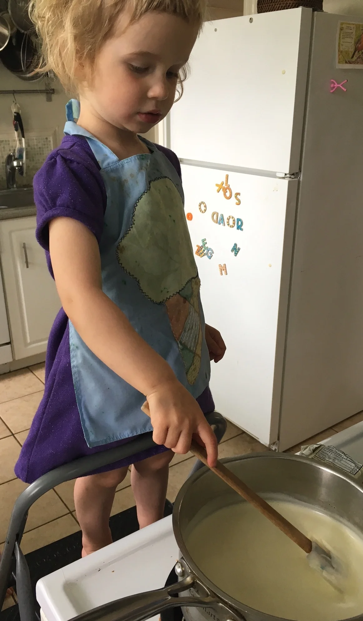 Polly (3) stirring the custard for the ice cream, as it thickens on the stove. She even chose a thematic apron for the occasion