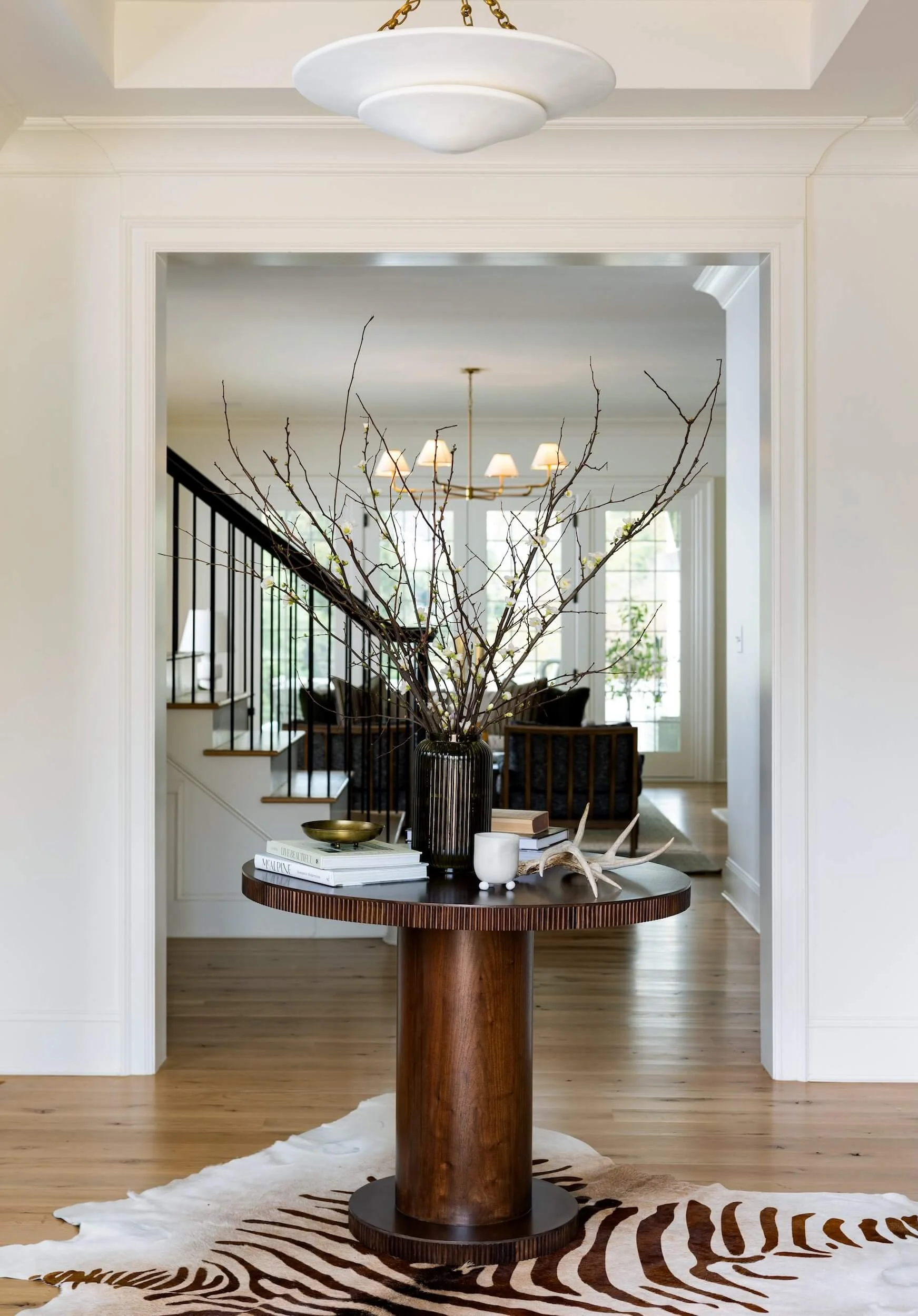 Pedestal table that sits in a doorframe in the entry way atop an animal skin rug