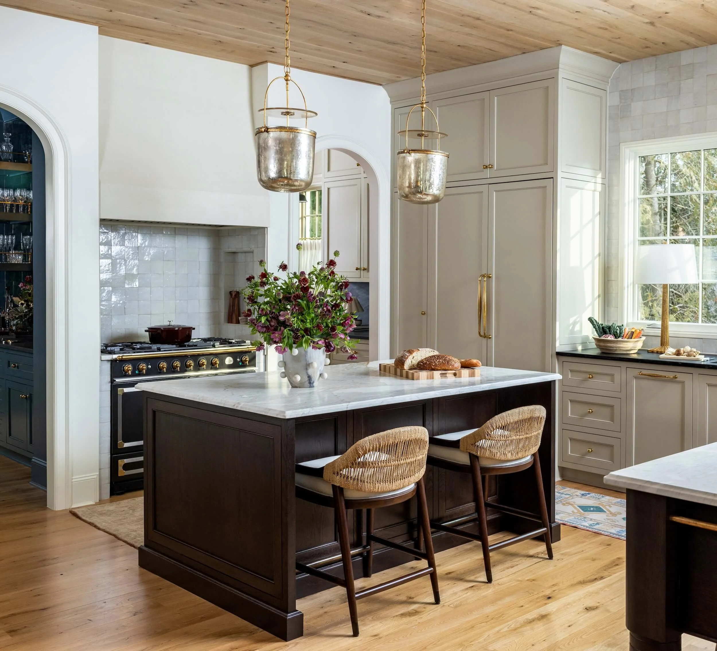 A view of one kitchen island with two barstools, and the gorgeous custom stove behind it
