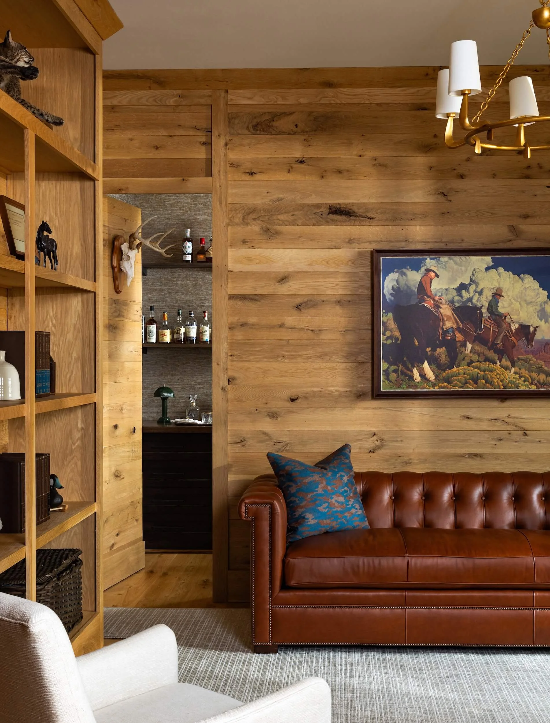 A wood paneled sitting room with brown leather couch and white chair
