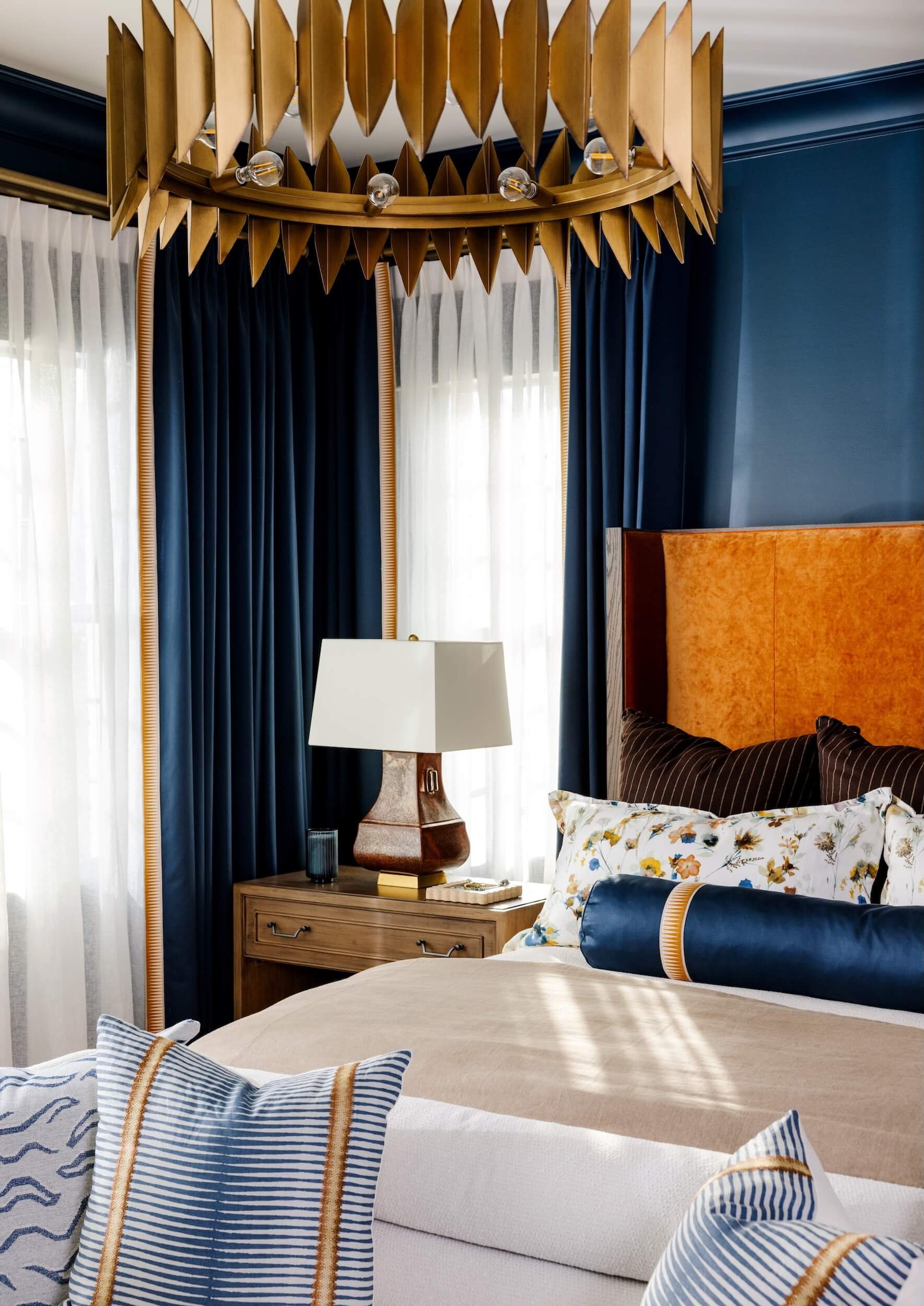 A look into the corner of the blue bedroom over the bed- focusing on the side table and golden leaf light fixture