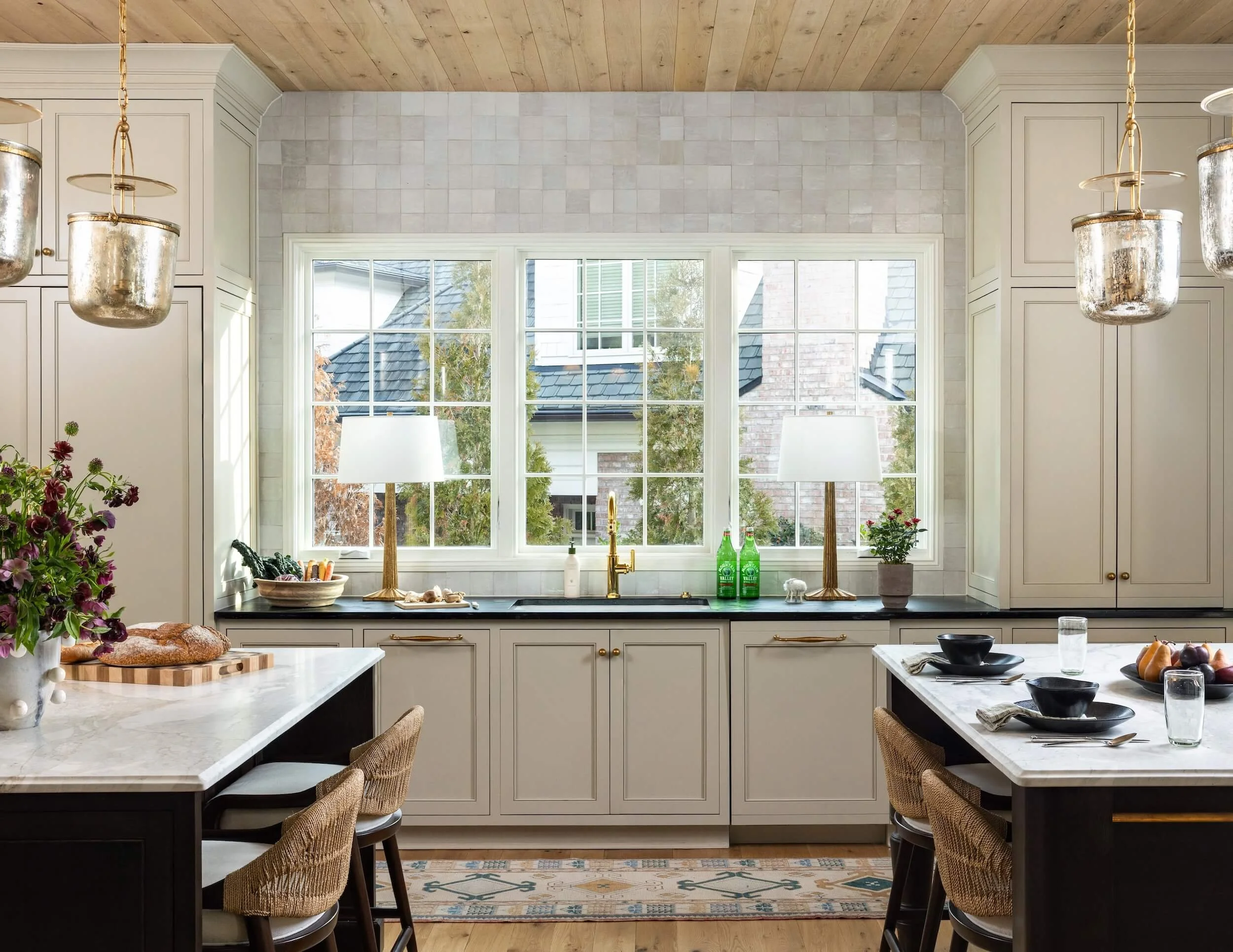 A look at the kitchen sink, surrounded by clay tile, three windows behind it and a view of the two eat-in islands
