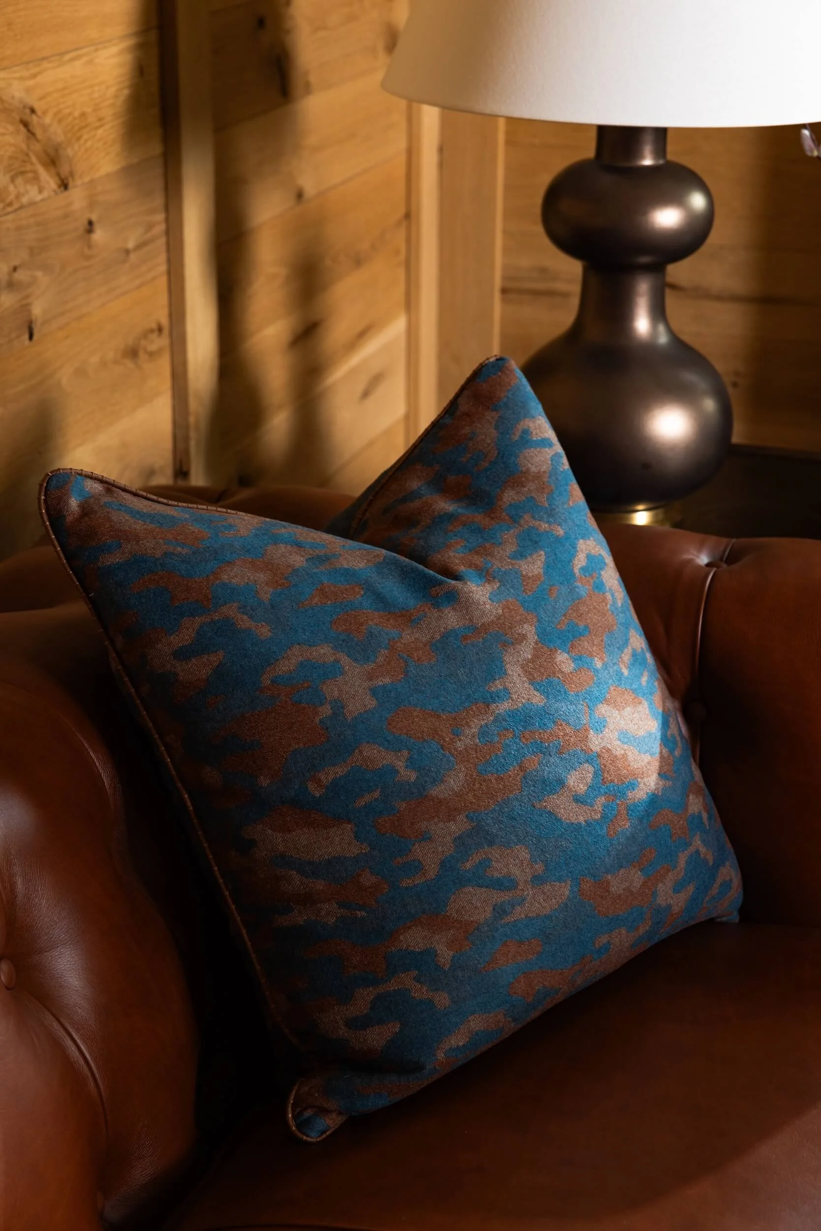 A close up of the blue and brown throw pillow on the leather couch