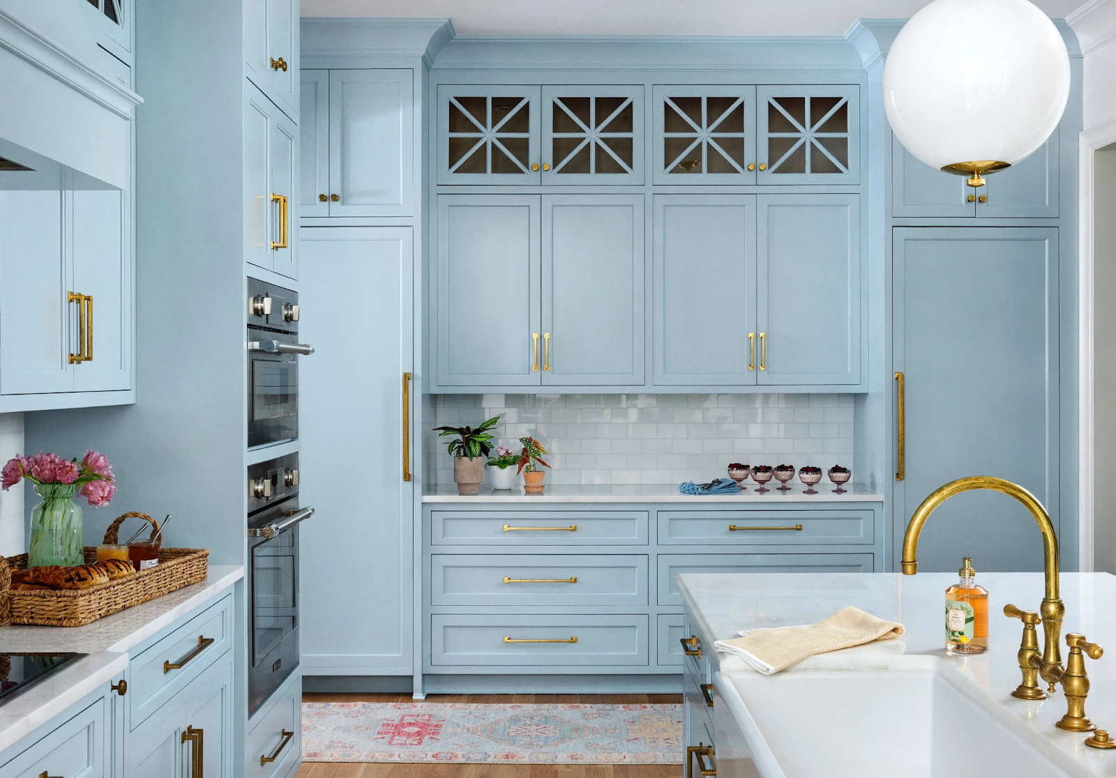 Traditional-style kitchen featuring light blue Farrow & Ball inset cabinets, exposed face-frame detailing, and brass plumbing and hardware with a natural living patina, from our Southern Proper project