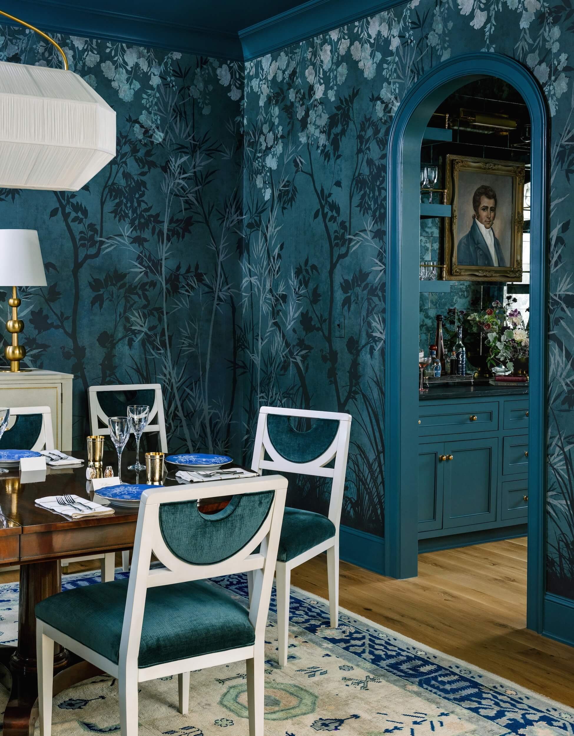 A view into the corner of the color-drenched dining room with a glimpse of the butler's pantry through the arched door frame