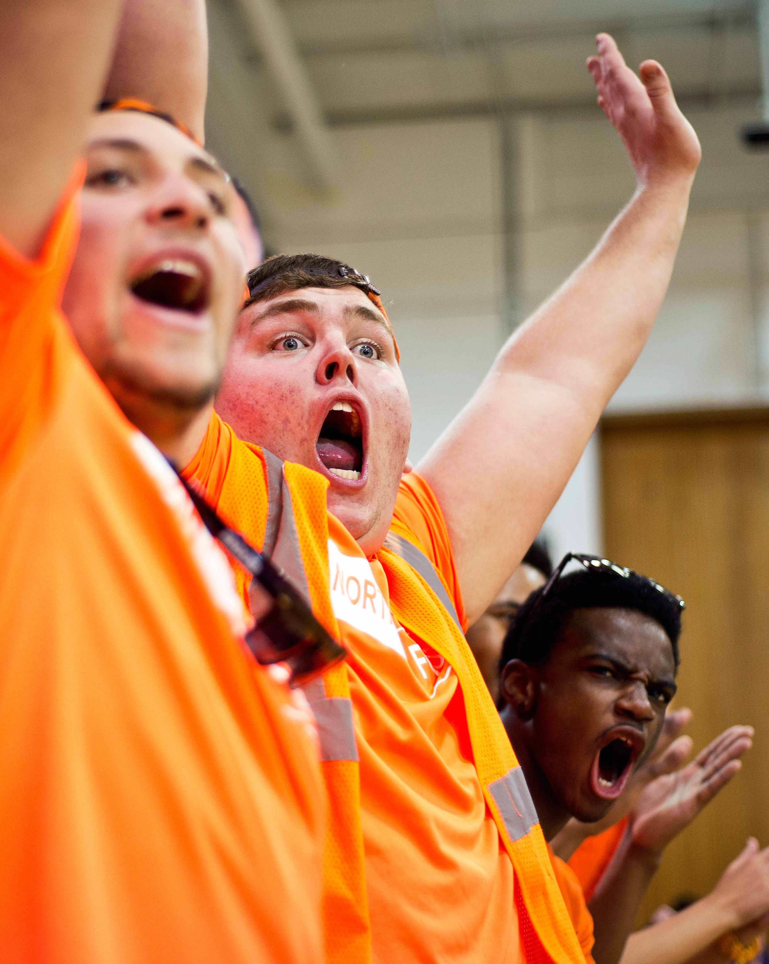 Arms in the air, senior Logan Miller cheers as the Cougars make a layup during the game on Feb. 21 at Shawnee Mission West. Spirit Club designated the game as an “orang-out,” so students wore orange to support the team. “I think it’s important to cheer because the players feed off the energy,” Miller said.