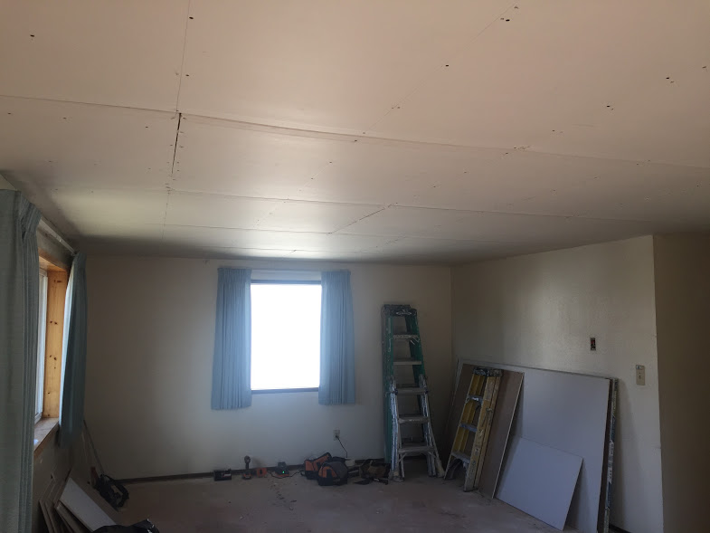 Drywall being installed over textured ceiling. The ceiling texture, commonly used in the past, has absbestos. Nowadays, it's cheaper and easier to simply cover it with another layer of drywall than to demo and dispose of it. Disposal of absbestos is possible to do, but very labor intensive. In Hillsboro, Oregon, one can dispose of it but it must be wrapped and tied and extra thick plastic bags. that are marked as toxic waste. They charge a lot for disposal as well, as they must cover the large bags with 2ft of dirt every night. 