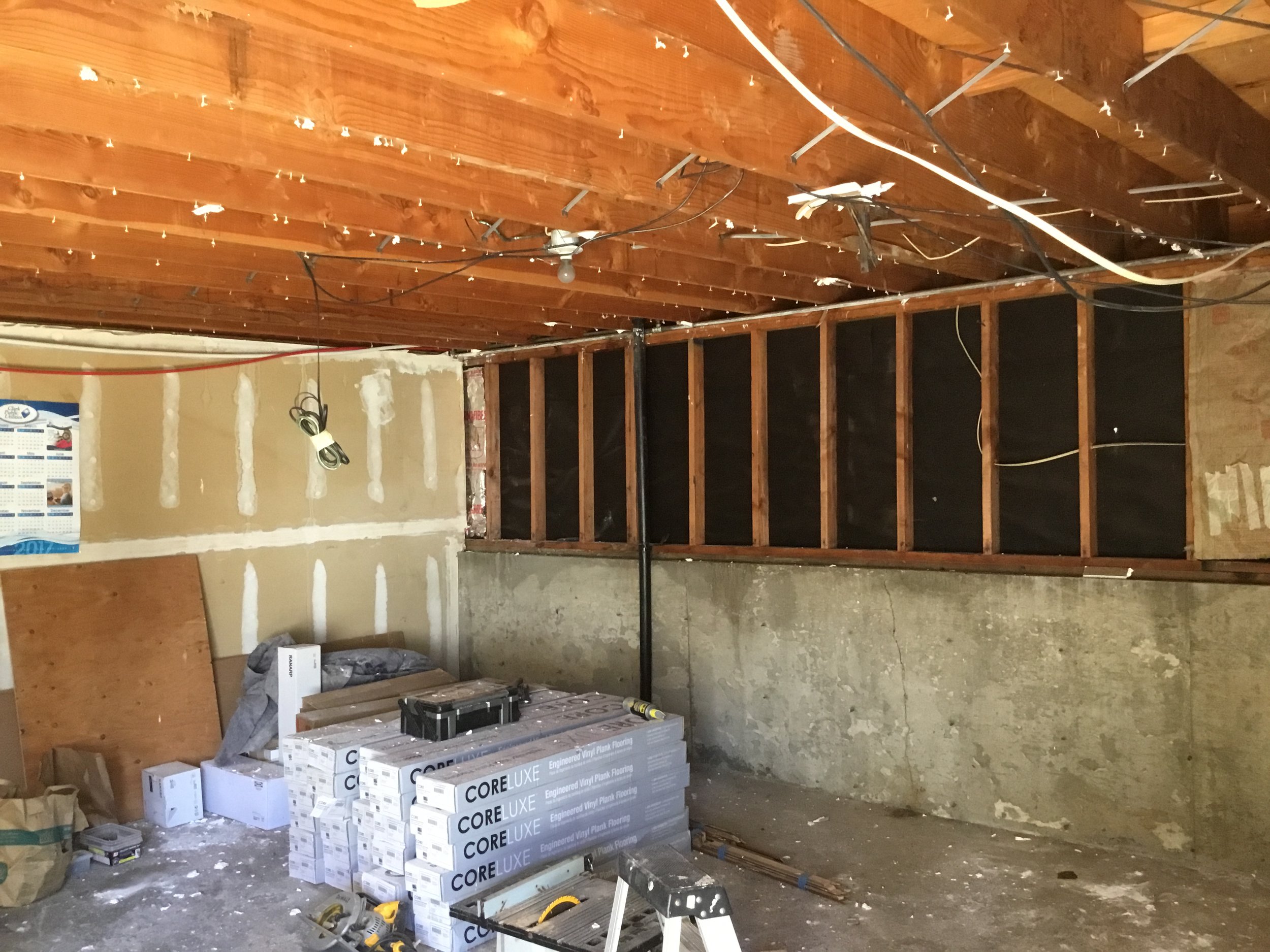 The ceiling drywall has been removed. For now, we'll use the ceiling bays for running plumbing and electrical to the upstairs unit. Eventually, I'll fill in the ceiling bays with insulation to deaden the sound between the upstairs and downstairs unit. The materials for the renovation are purchased and ready for installation. The garage is used as a staging area for these materials. 