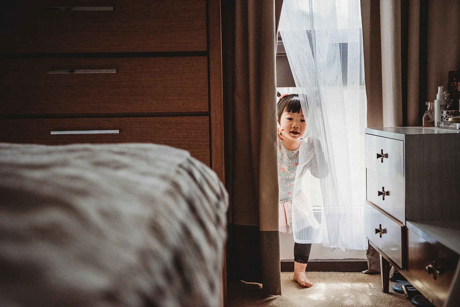 little girl peeking through curtains
