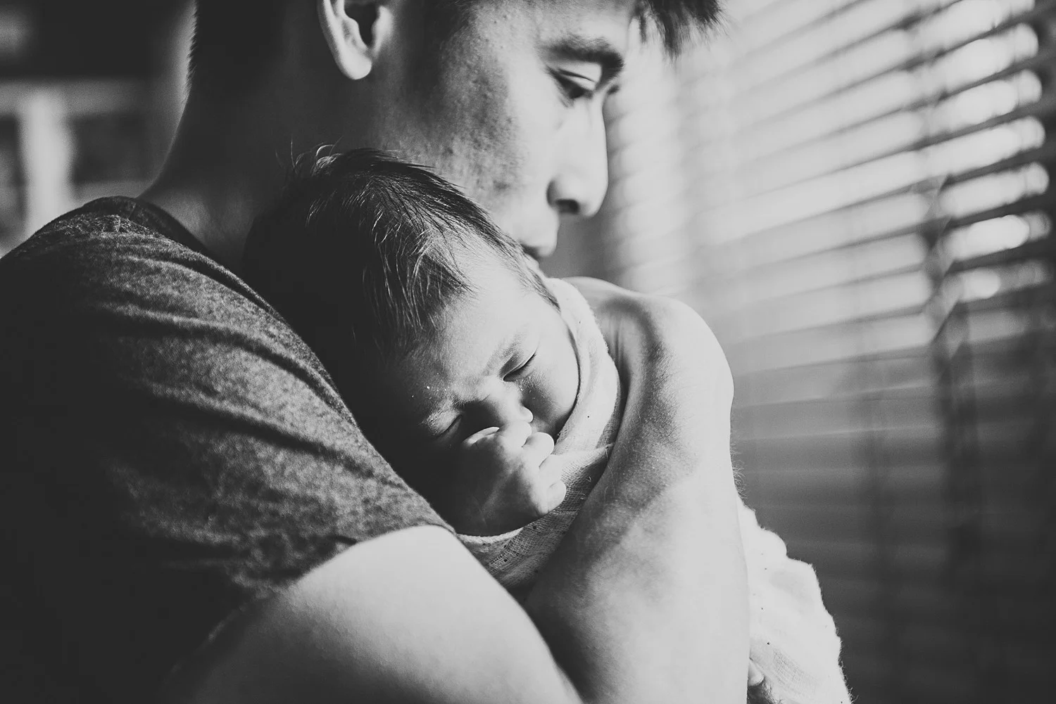 father cuddling newborn baby