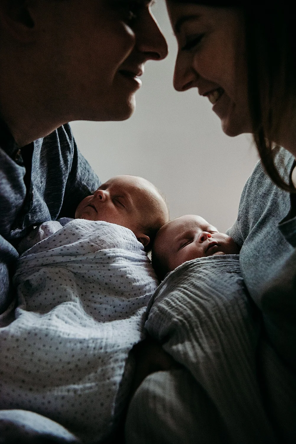 daddy kissing mums forehead with twin newborns