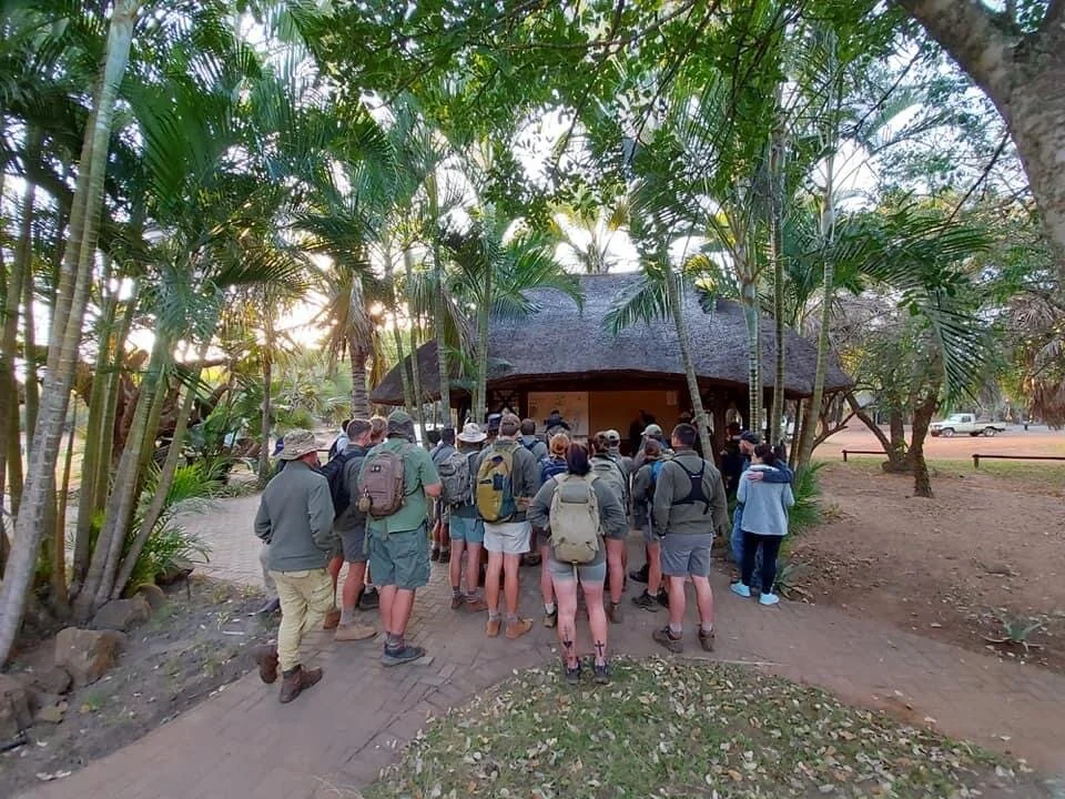 The team huddles together for a morning briefing before moving out into the wilderness to begin their snare removal mission.