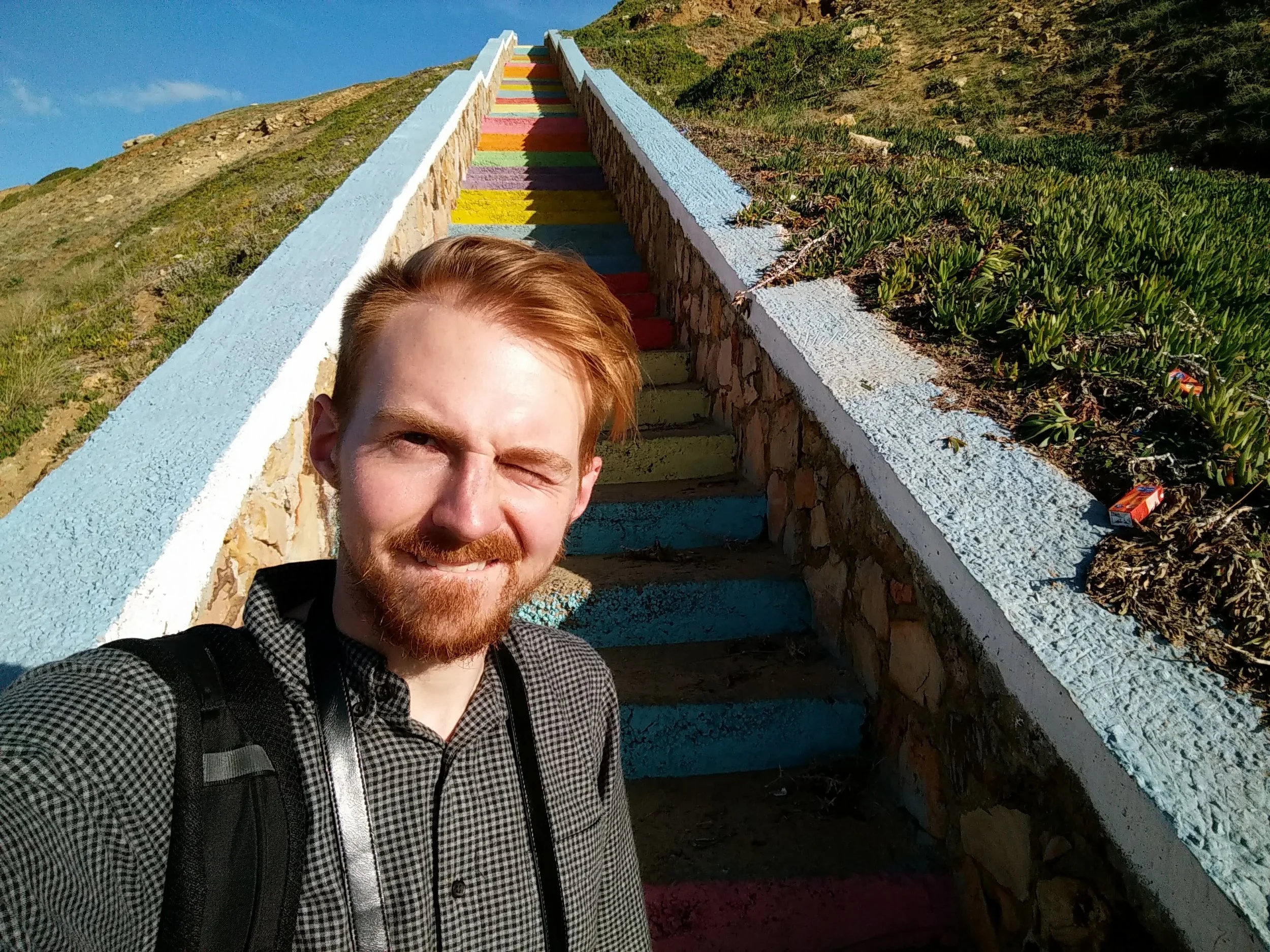 Selfie in front of some rainbow stairs leading up from a beach in Morocco.