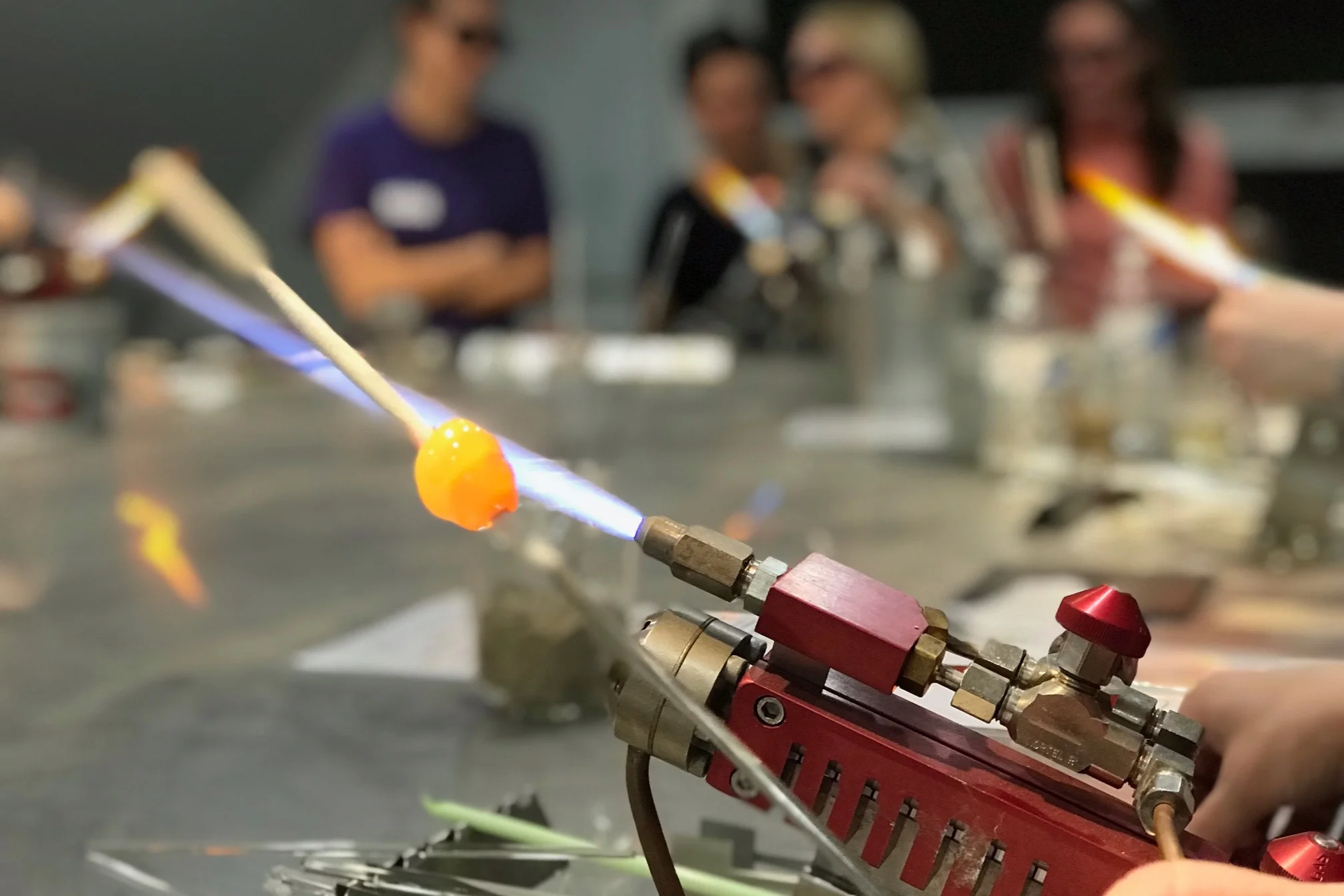 Student using a torch to melt glass and make a bead.