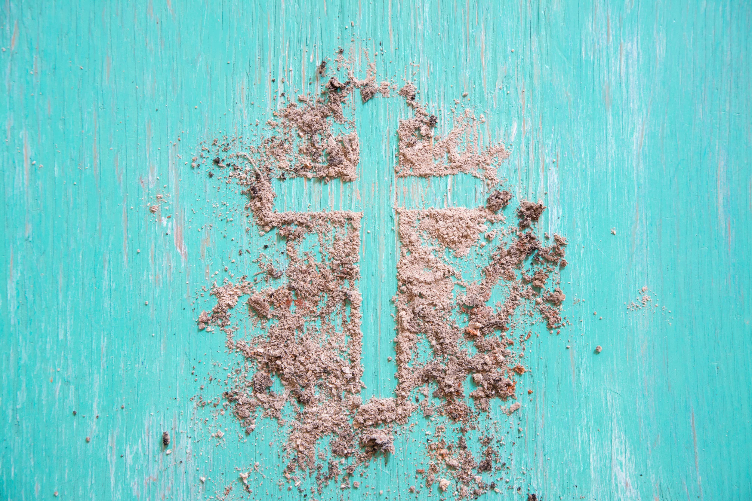 Cross in sand on teal wood.jpeg