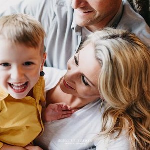 A woman, a man, and a young boy smiling and smiling together indoors.