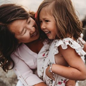 A woman and a young girl sharing a joyful moment, close together, smiling and showing affection.