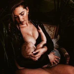 A woman breastfeeding a baby indoors in a cozy setting.