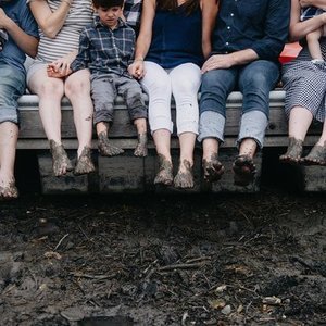 People sitting on a dock with their feet hanging over the edge, dipping into water.