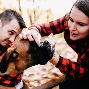 Two women interacting with a large dog outdoors in a forested area.