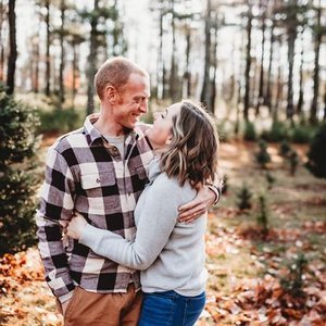 A happy couple embracing in a wooded park during autumn.