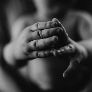Close-up of child's hands clasped together in prayer or contemplation.