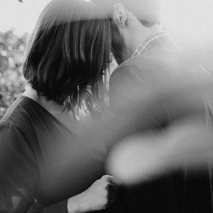 A couple is kissing outdoors. The image is in black and white.