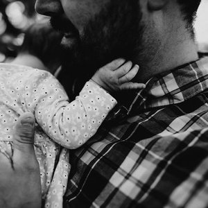A person holding a small child who is reaching out to touch the person's face