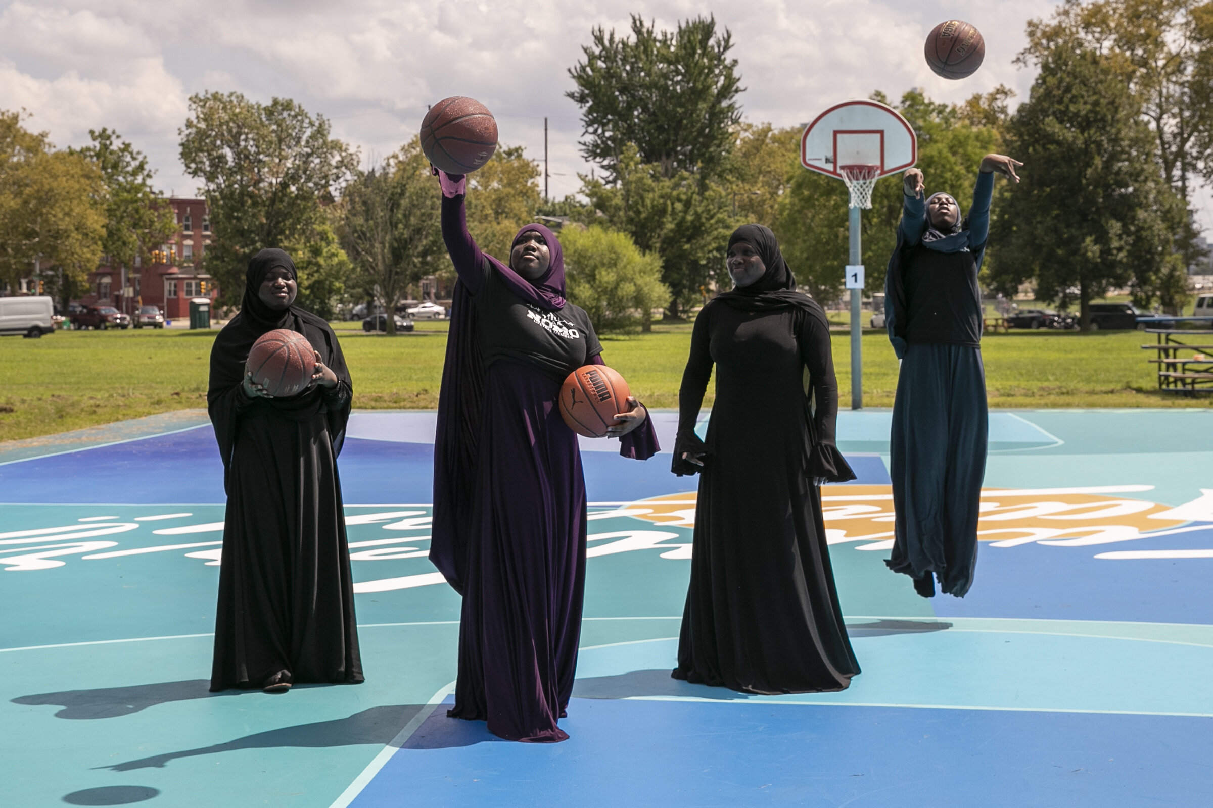  Khadijah Smith, 12, center left, holds two basketballs while she plays with Safiyyah Smith, center right, Baseerah Tucker, far right, and Ruqayyah Bibbs, left, on the refurbished and repainted basketball court at East Fairmount Park in the Strawberr