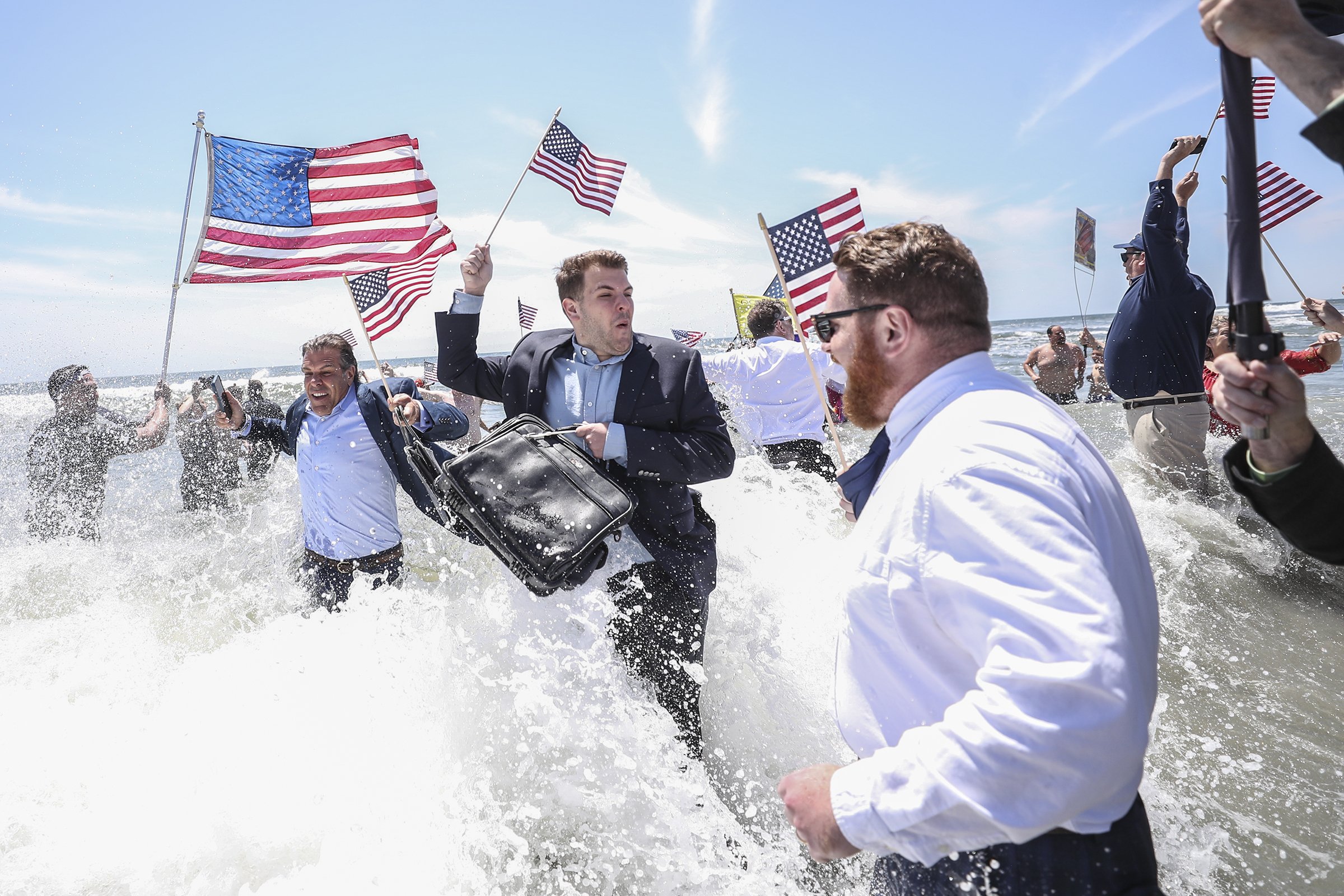  Participants react as a wave crashes on them during the annual Business Persons Plunge in Ocean City, NJ on May 26, 2023. In this Memorial Day Weekend tradition, city officials and community members  "unlock the ocean" for the season, first by turni