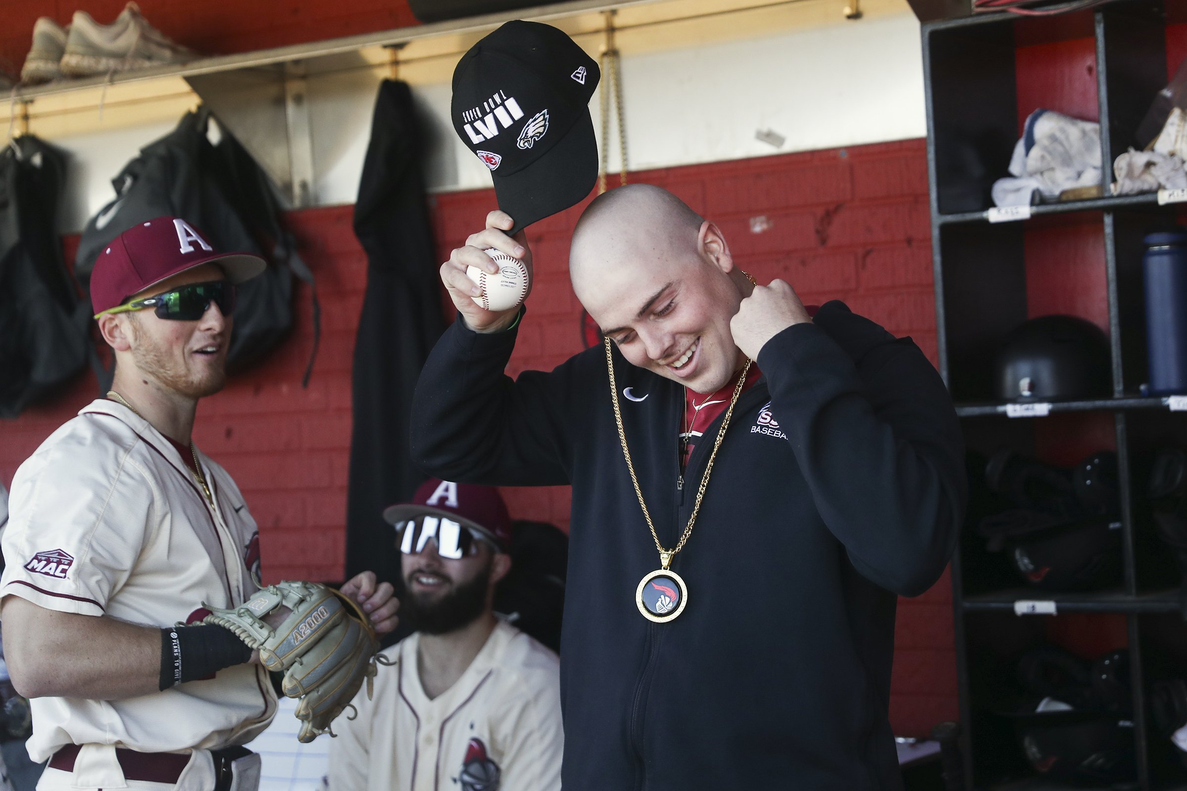  Luke Smith smiles while putting on a chain he received from Alex Madera, left, in the Arcadia dugout before their season-opener against Ursinus at Skip Wilson Field in Ambler, Pa. on Feb. 23, 2023. Luke Smith had hopes to be drafted this summer as h