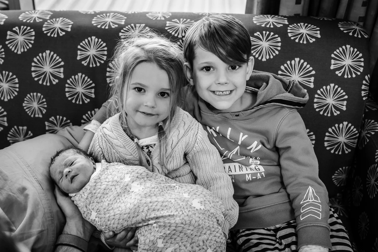 first photo of all three siblings sitting on couch
