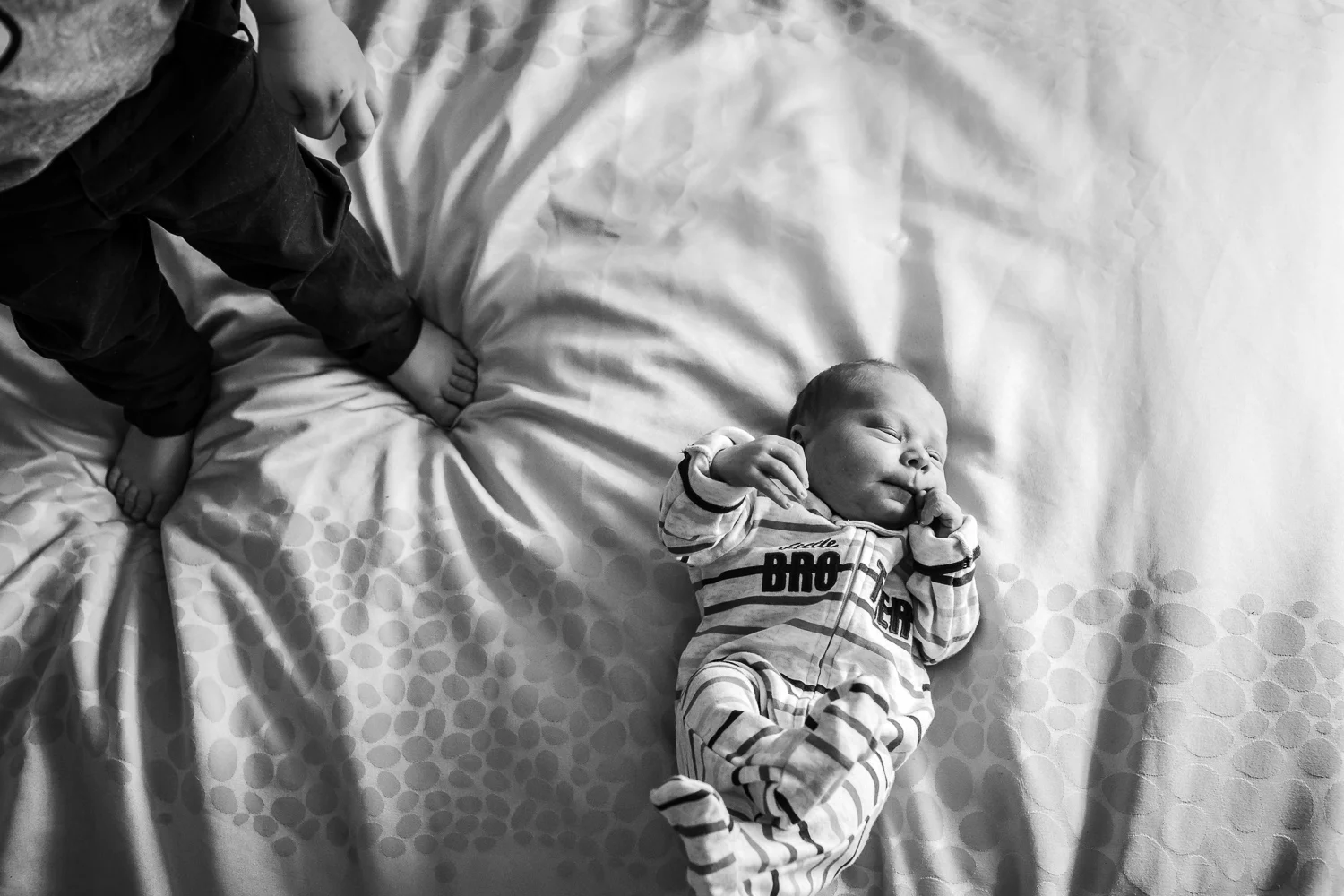big brothers feet and little brother on bed during newborn lifestyle session, Melbourne