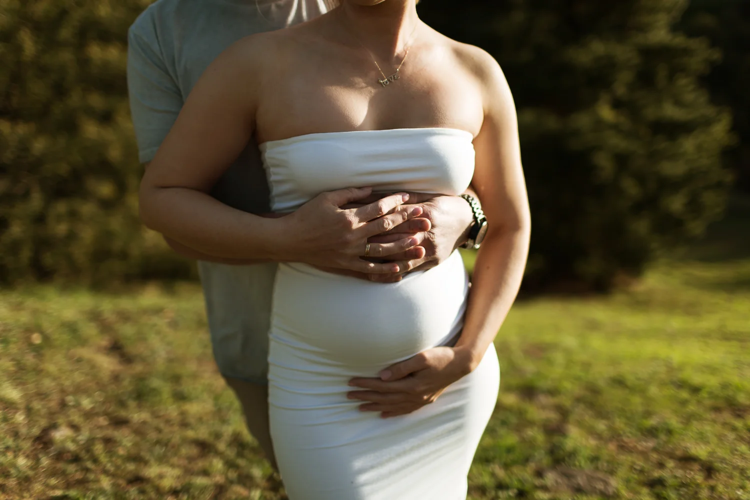 beautiful pregnant belly starting to show at 12 weeks surrounded by hands of love.