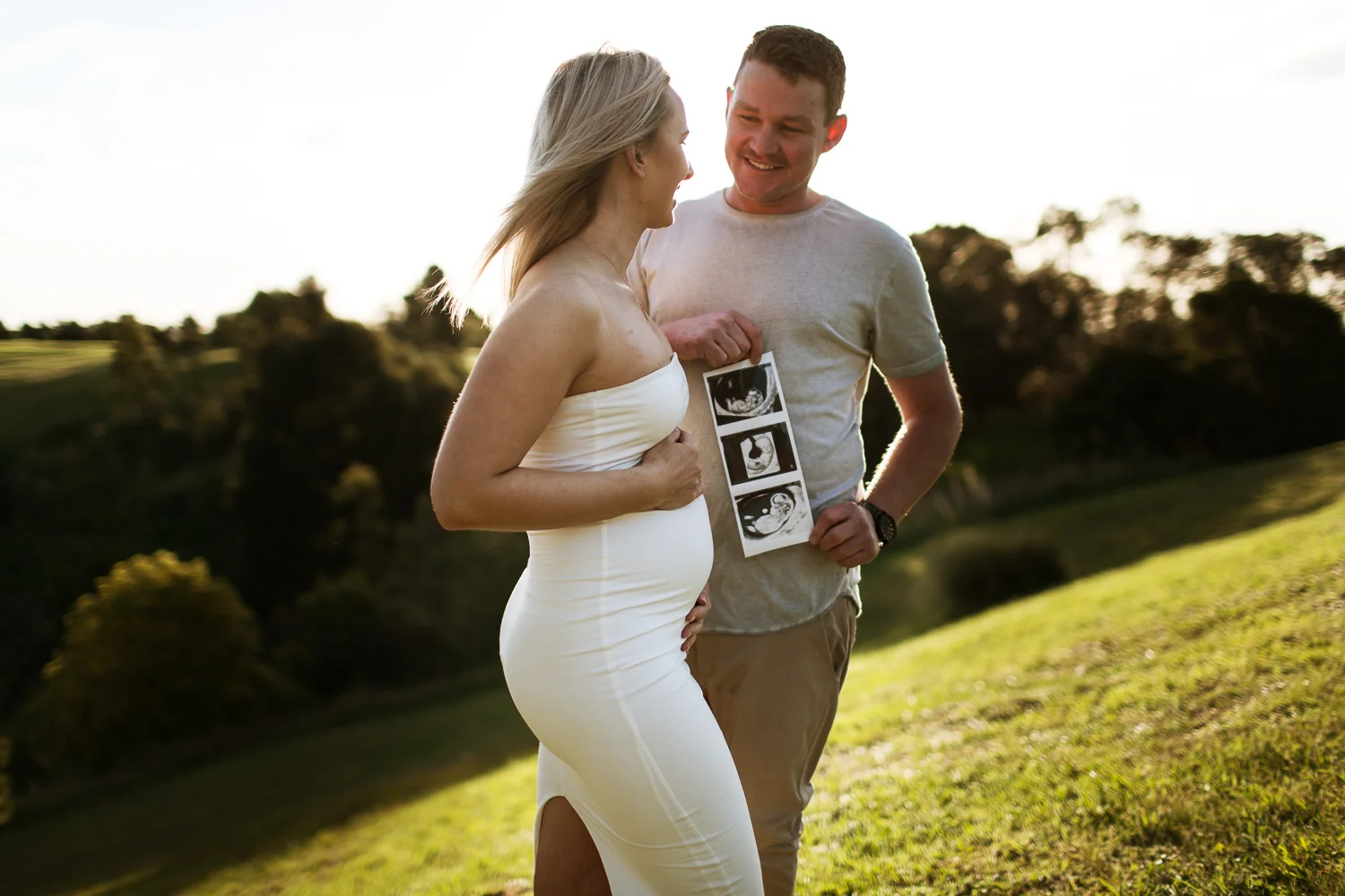 couple ready to announce they are waiting for a baby. Mum holding belly, dad holding scan.