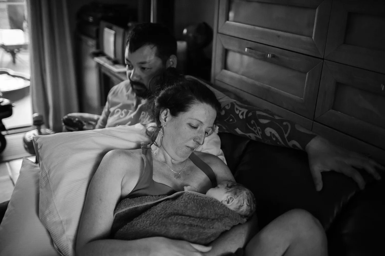 mother embracing newborn after first feed at intimate home birth