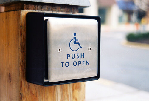 An external silver accessibility button which reads push to open