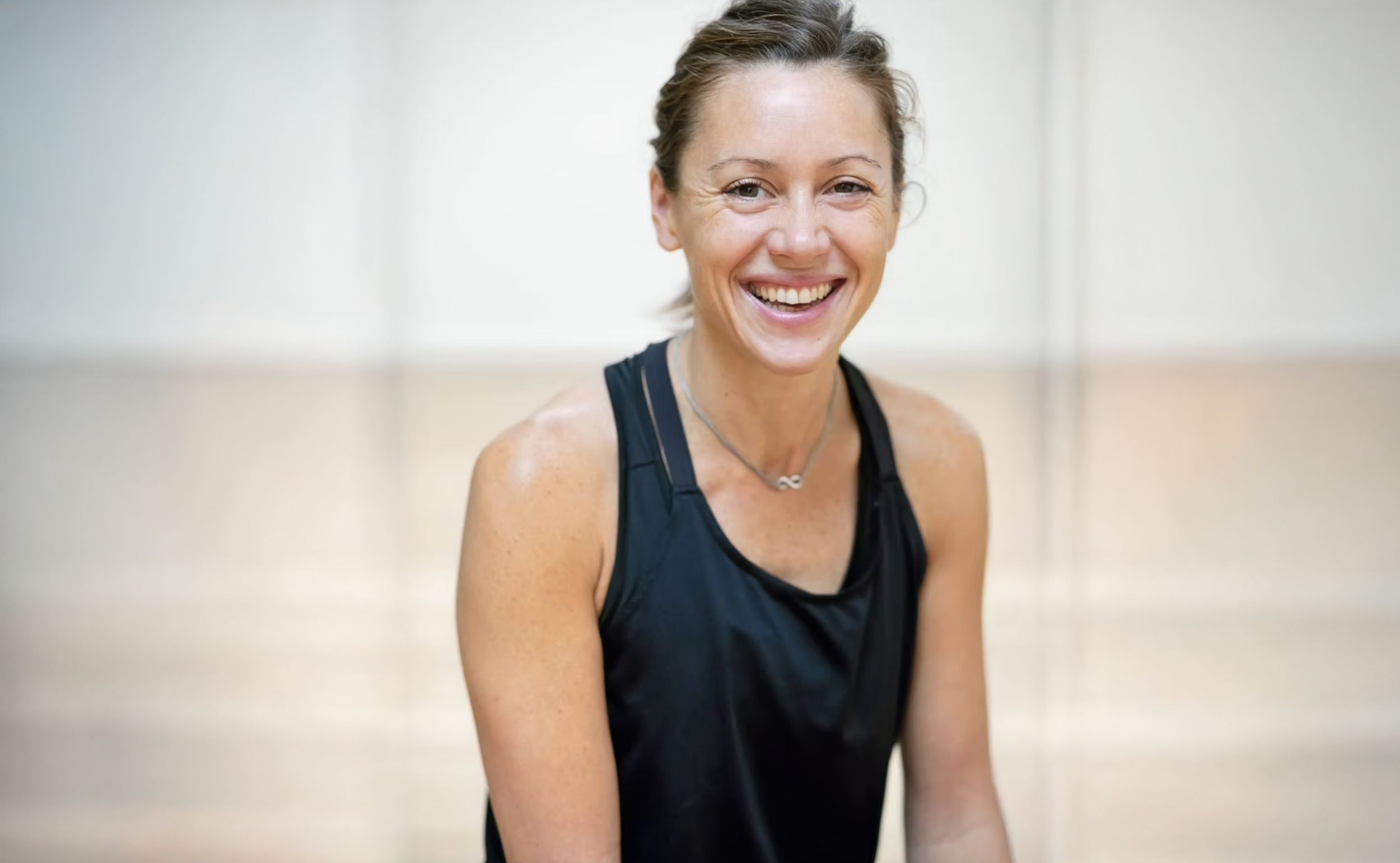 Une femme souriante portant une tenue de sport dans une salle de sport