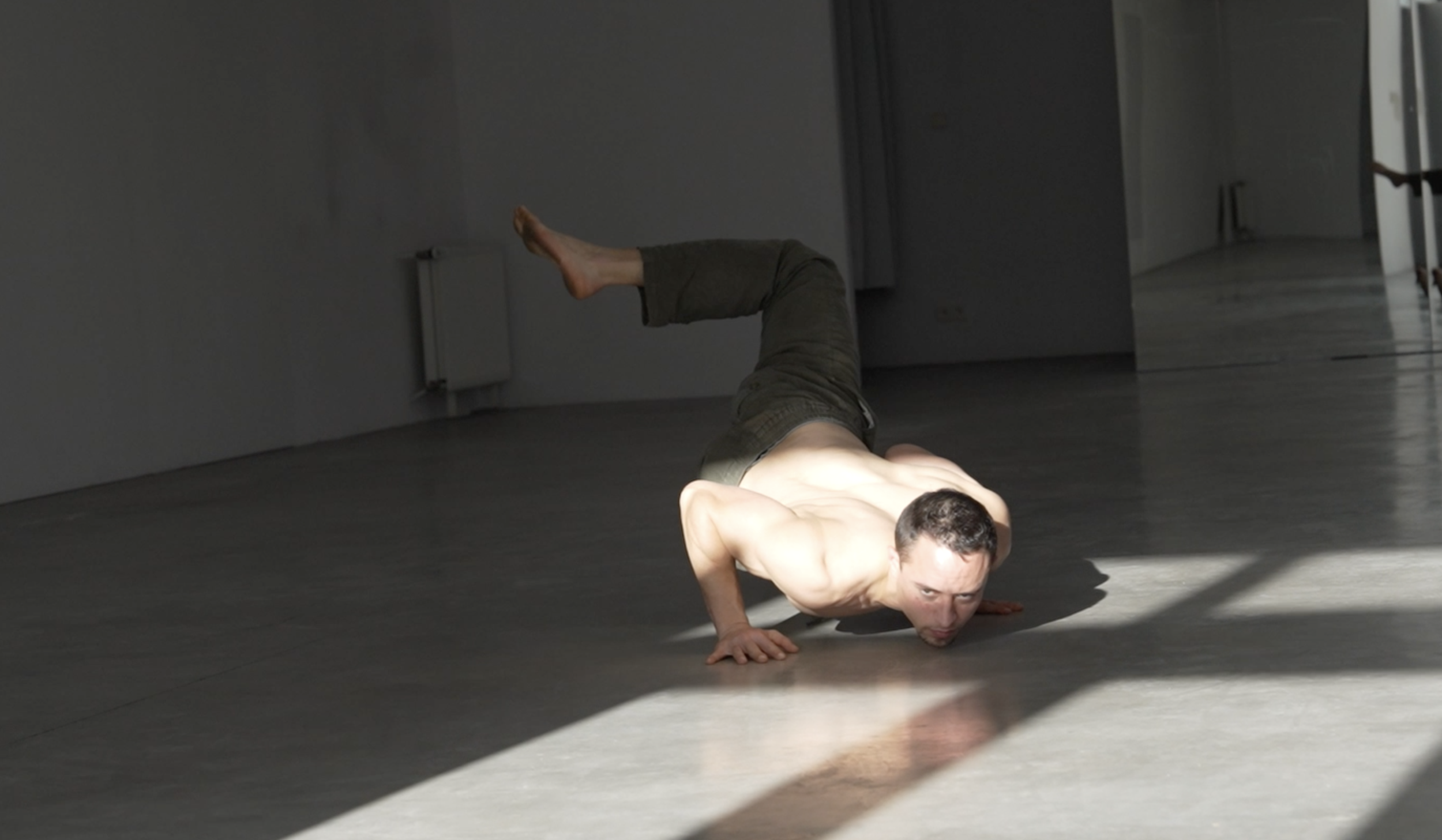 Homme sans chemise faisant une pose de planche latérale dans un espace intérieur avec lumière naturelle