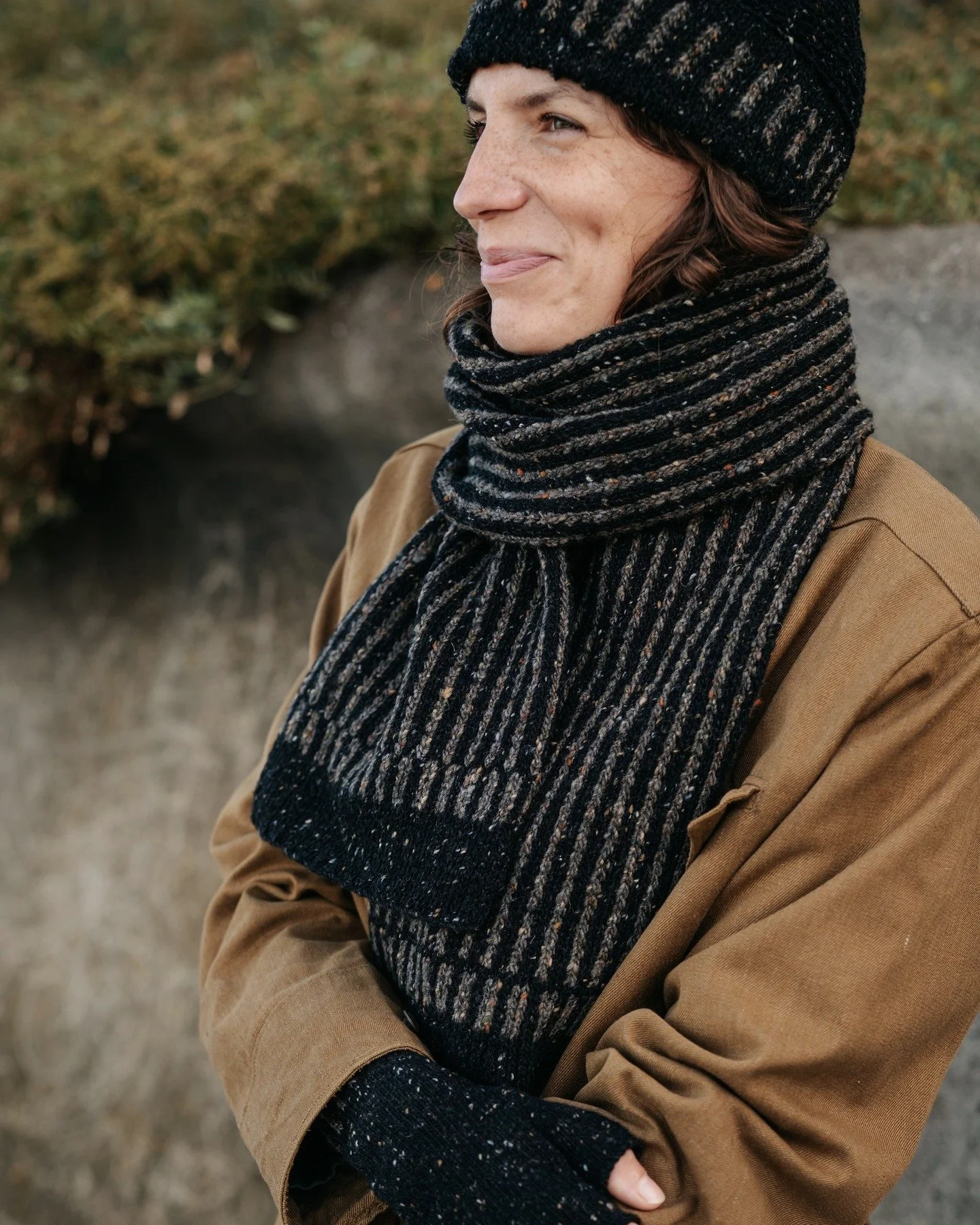 We're moving slowly towards Spring but a scarf is still required to protect against seasonal chills. Amina wears the Donegal Wool scarf, hat and mittens in black and vole colour way.