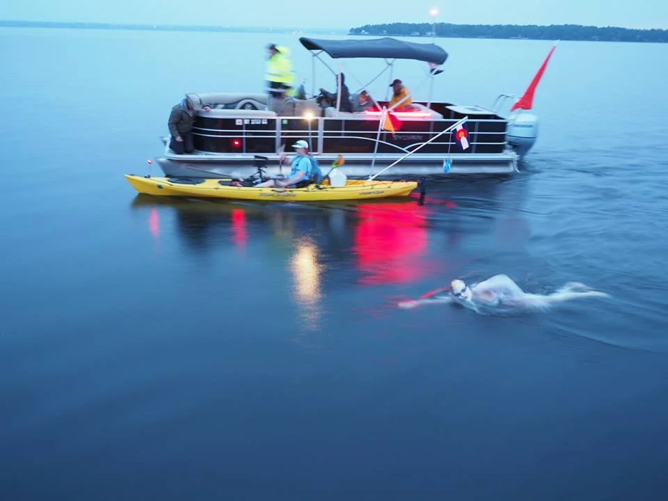 Tackling a swim at dusk with her team's support. PC: Ken Classen. 