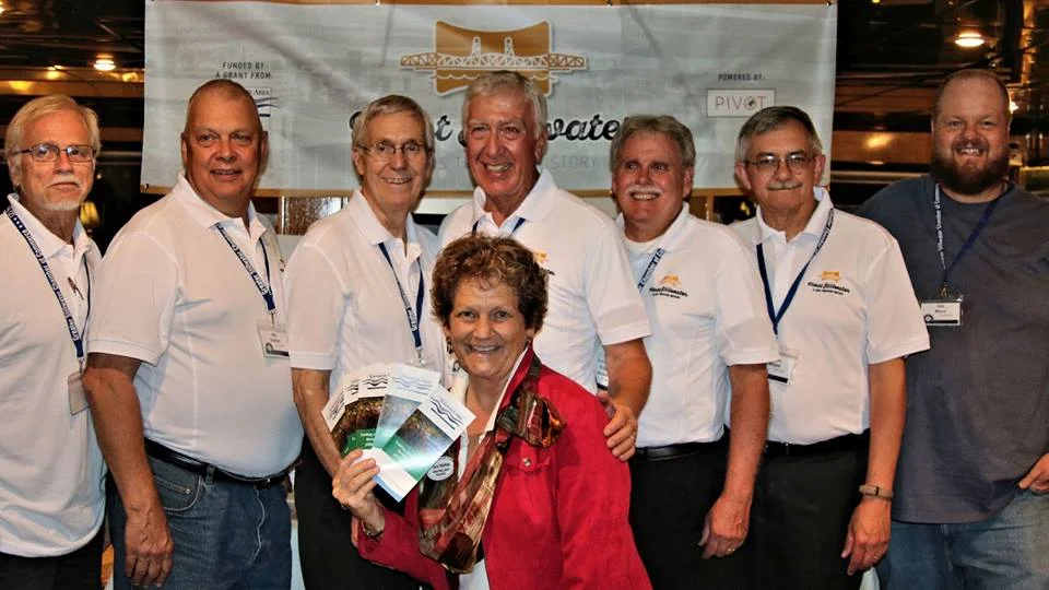 Lens Flare Stillwater Volunteers, left to Right, Gary Bressler, John Buettner, Bill Fredell, Bob Molenda, Dick Marlow, Tom Wieland, John Moore. In front is Miriam Simmons from the St. Croix Valley Foundation. The event is the 125th Anniversary of the Greater Stillwater Chamber of Commerce, September, 2016. Mark Luebker, who lives in South Dakota is not in the photo.