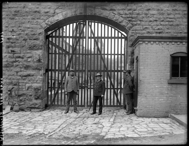 This photo was taken by John Runk in 1907. It is the front gate of the Territorial prison which was located on the west side of Main Street. The image shows the guard and two trustees outside the gate. To View a "Time-Tunnel" photo of this same location that allows you to travel from 1907 to 2016, just click or tap on the above photo.