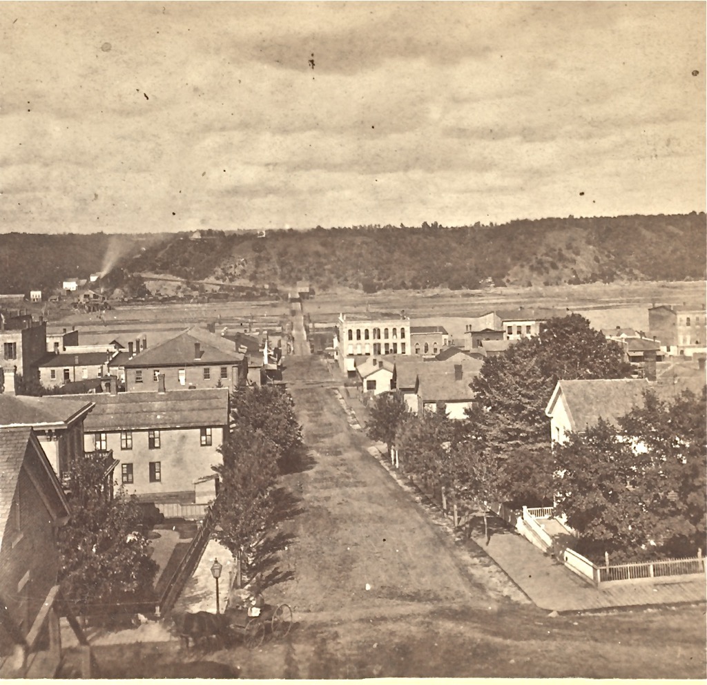 This vantage point is from the Chestnut Street Stairway, taken in the 1870's by John Sinclair. You can see the first bridge in the background along with a lumber mill on the Wisconsin side of the St. Croix River. In the left center, you can see the Brunswick House and the brick building to the left of the stairway. This was before the streetcars first came to Minnesota. Photo courtesy of the Washington County Historical Society and Mr. Brent Peterson, executive director, WCHS. To view a "Time-Tunnel" photo of this same location from the 1870's to 2016, just Click or Tap the above photo.